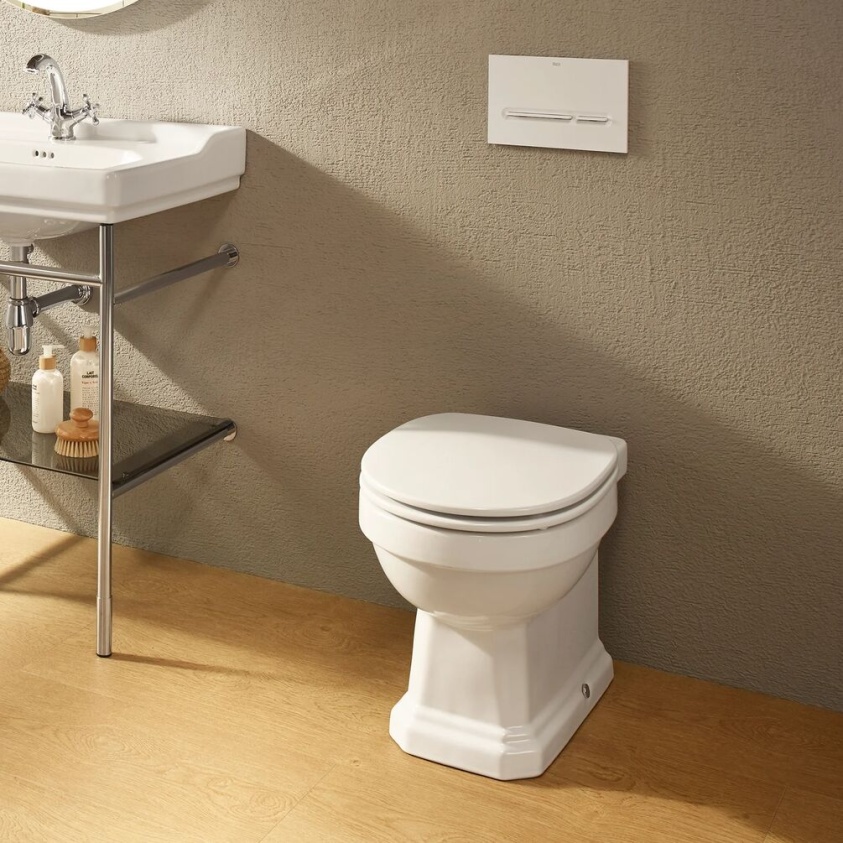 Lifestyle image of the Roca Carmen Rimless Back to Wall Toilet installed in a bathroom next to a basin with stand